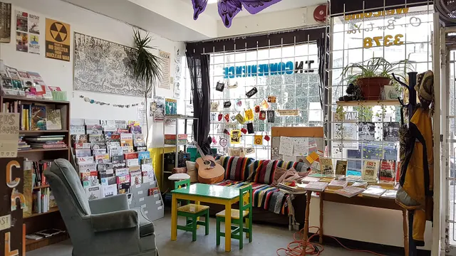 Sunlight shines through the window onto the hangout zone at Spartacus Books, which includes a couch, comfy chair, guitar, colourful magazine rack, posters, and patches. Books and literary culture reporting: a practical guide