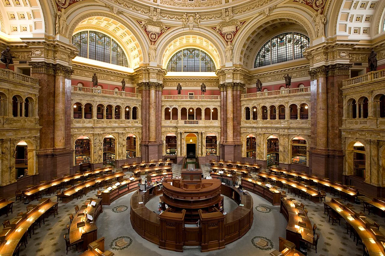 The Main Reading Room of the Library of Congress with circular desks, bookshelves, arches, and a high decorated ceiling