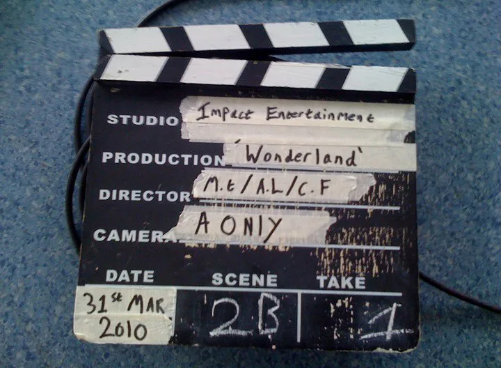 A traditional wooden clapperboard marked with production, camera, date, scene, and take information
